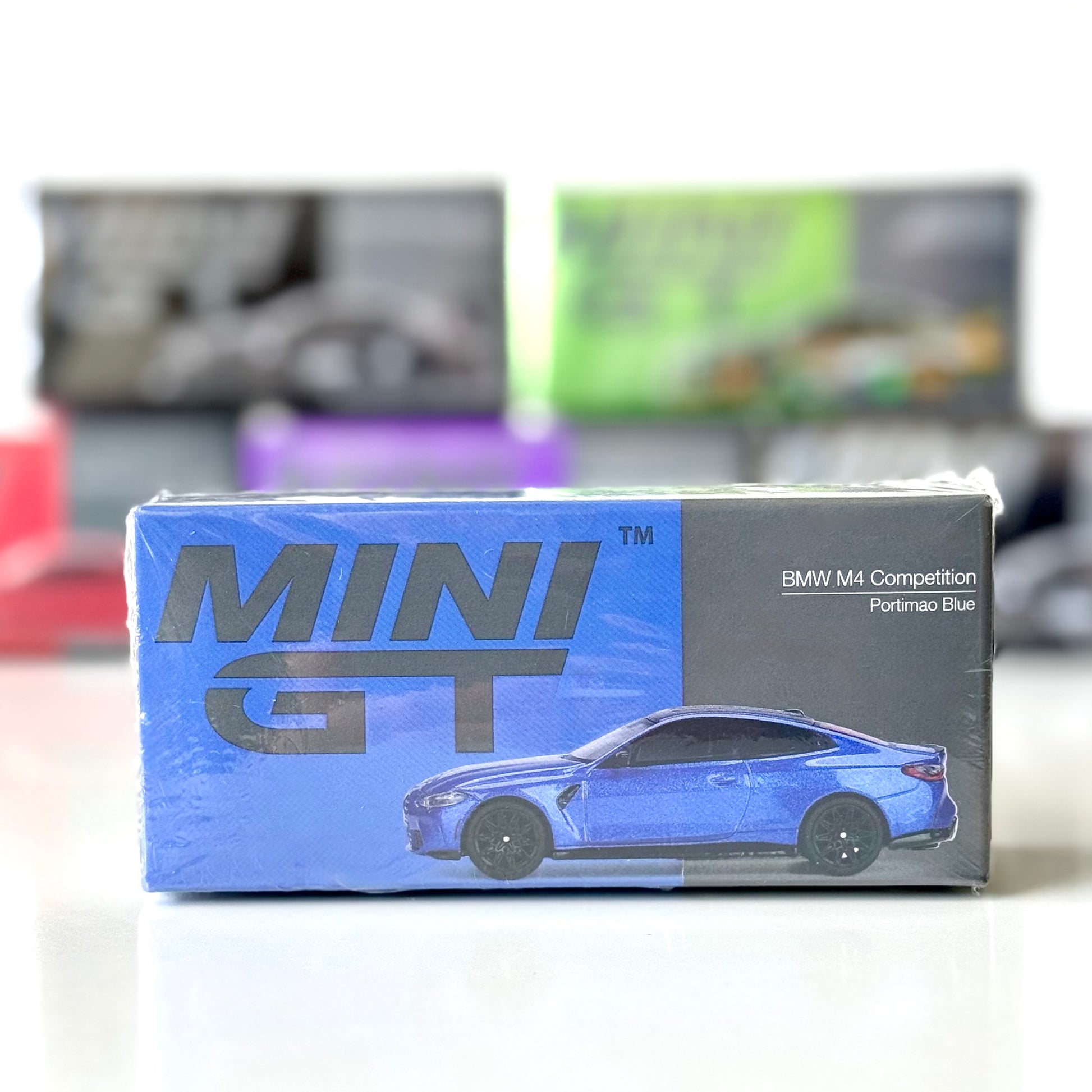 Front of boxed BMW M4 Competition Portimao Blue RHD 1:64 model by Mini GT