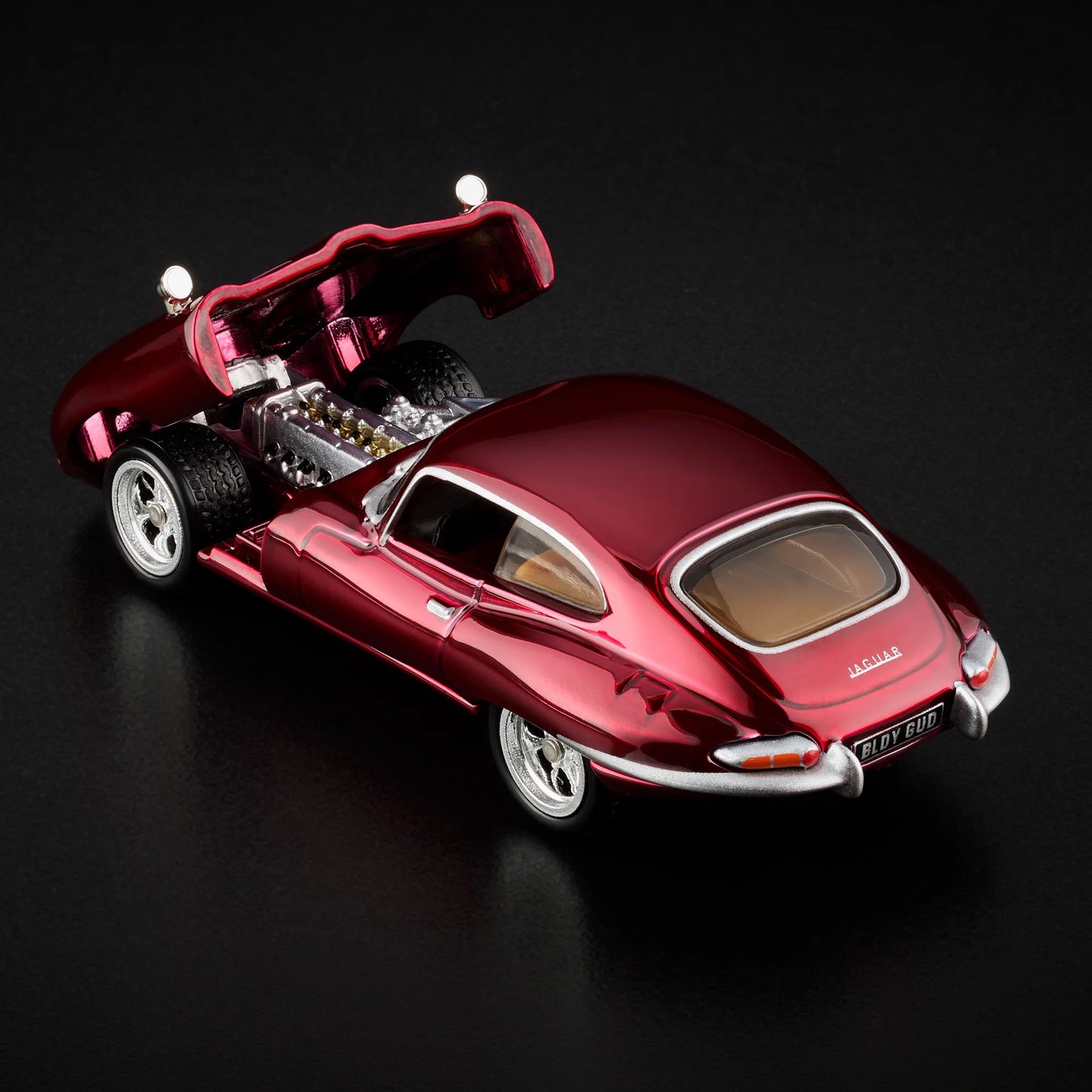 Close-up of engine replica under open hood of loose Jaguar E-Type model