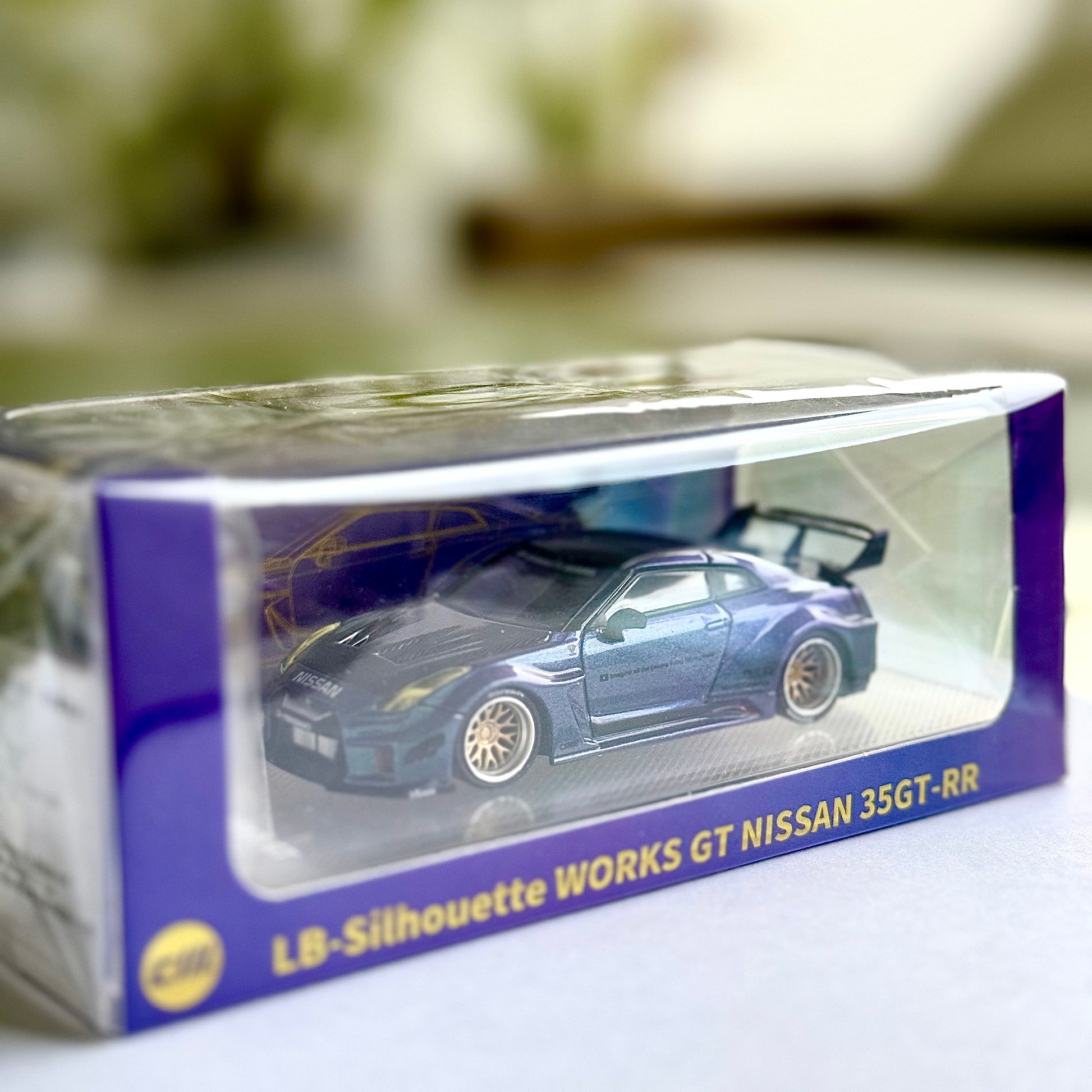 Nissan LBWK 35GT‑RR Chameleon with Carbon diecast in display base – front angle view